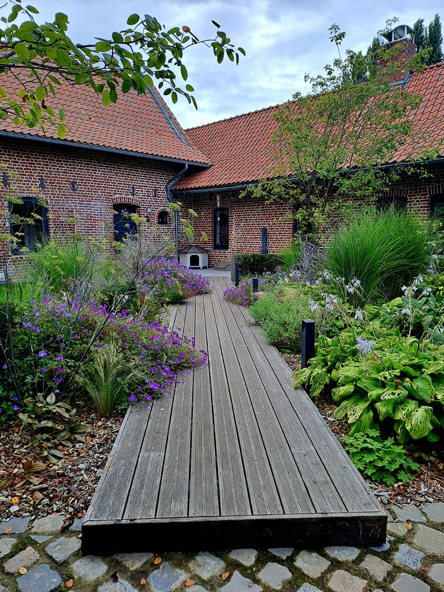 Allée en bois avec couverture de plantes et fleurs.